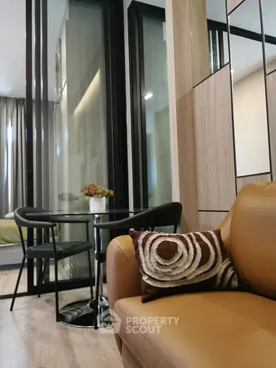 Modern living room with stylish decor and glass partition leading to bedroom
