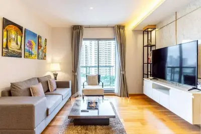 Modern living room with large TV and city view, featuring stylish decor and cozy seating.