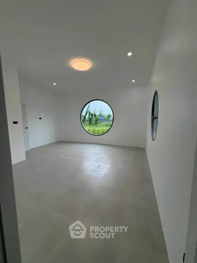 Spacious modern room with unique circular windows and minimalist design.