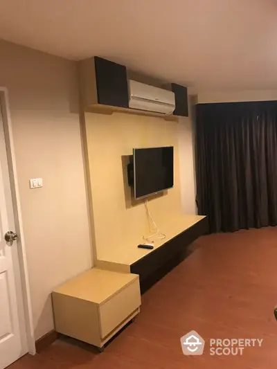 Cozy living room interior with modern entertainment wall unit, flat-screen TV, and air conditioning in a well-maintained apartment.