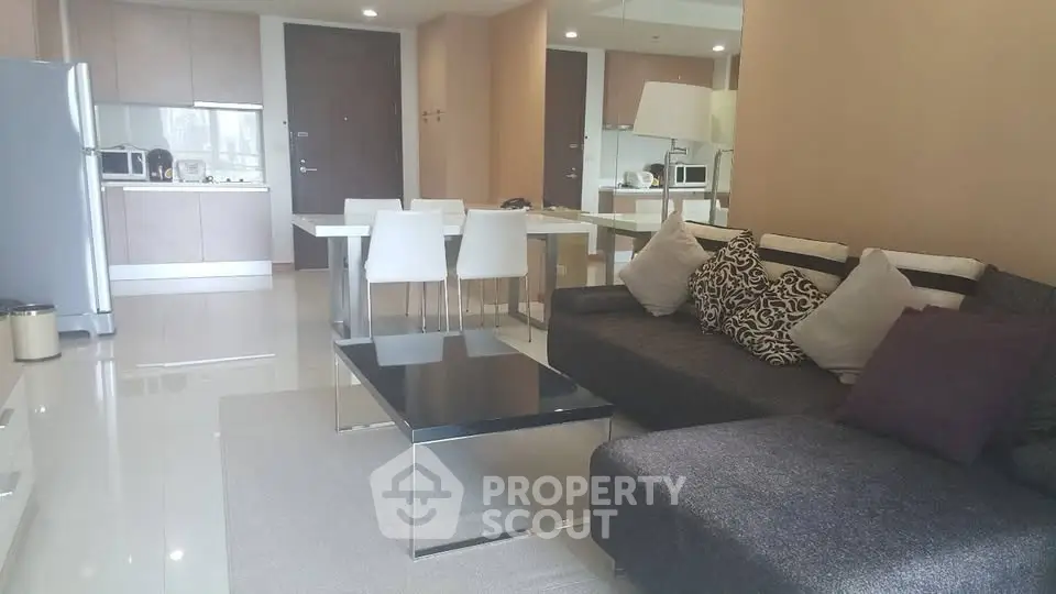 Modern open-plan living room and kitchen with sleek furniture and neutral tones.