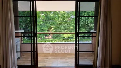 Spacious balcony with lush green view through sliding glass doors, perfect for relaxation.