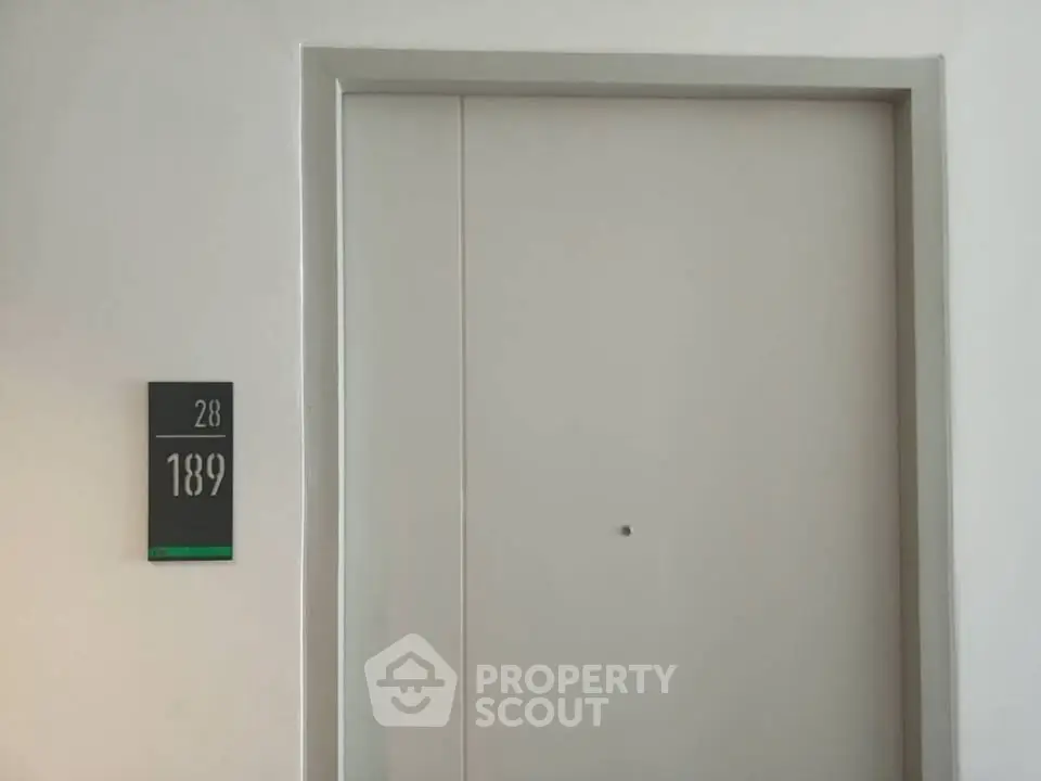 Modern apartment entrance with sleek door and room number signage.