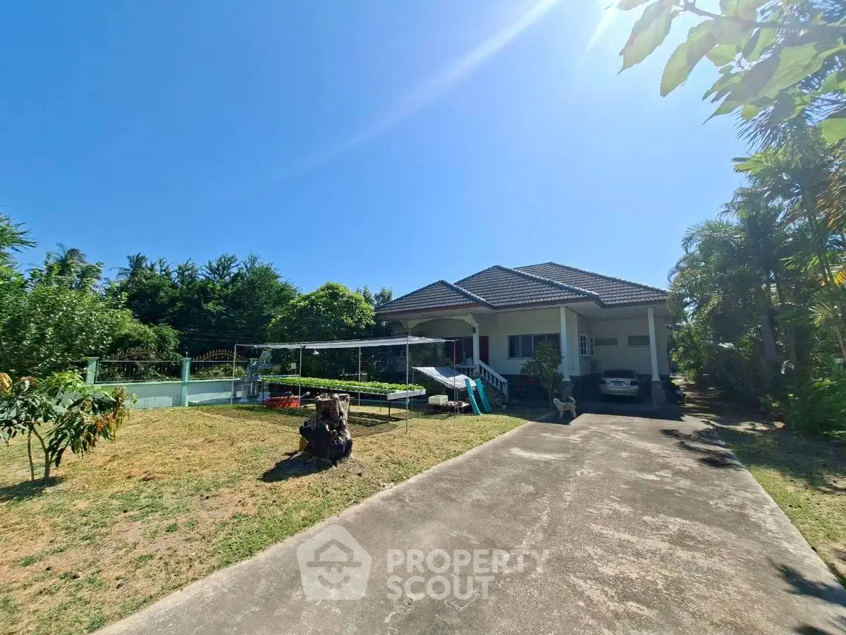 Charming single-story home with spacious driveway and lush garden under clear blue sky.