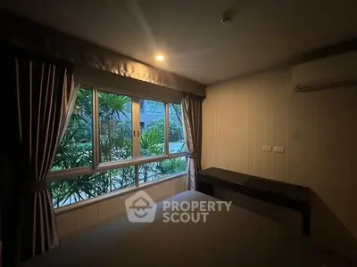 Cozy bedroom with large window and garden view, featuring elegant curtains and air conditioning.