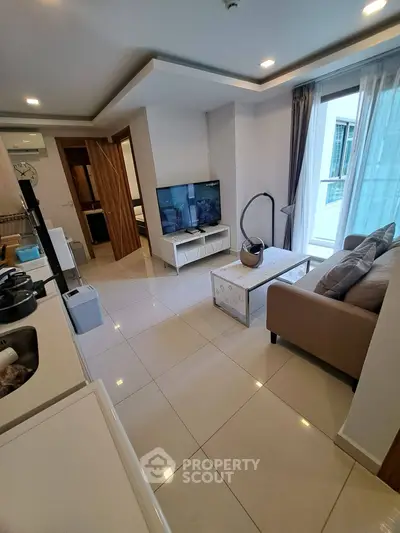 Modern living room with sleek design and natural light, featuring a cozy sofa and flat-screen TV.