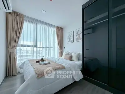 Modern bedroom with large window, elegant decor, and sleek wardrobe in a stylish apartment.