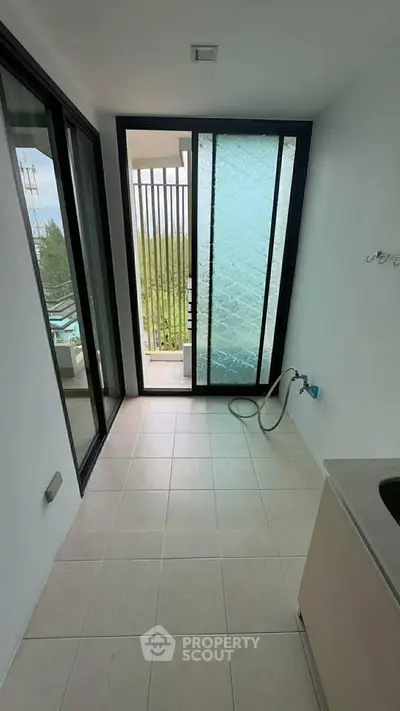 Modern utility area with glass door leading to balcony, featuring sleek design and natural light.