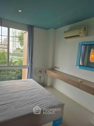 Bright bedroom with large window and modern air conditioning unit in urban apartment.
