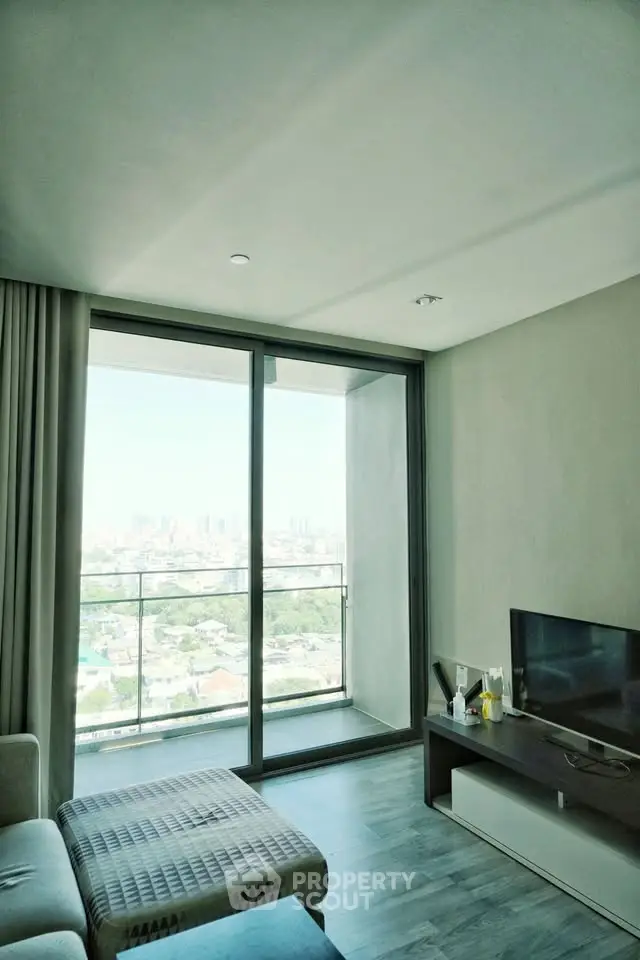 Modern living room with large glass doors opening to a balcony with city view