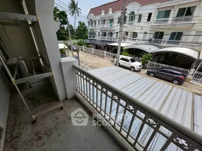 Charming balcony view in a residential neighborhood with street and parked cars.