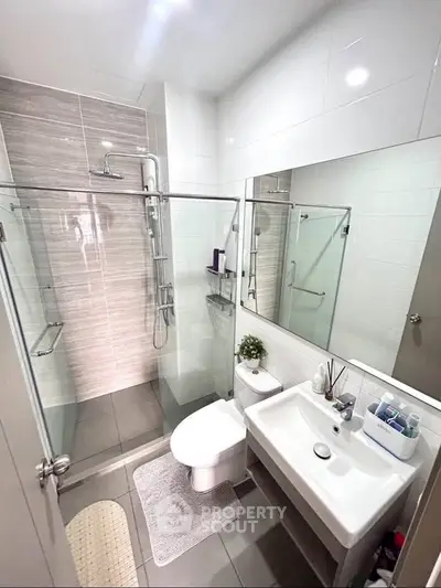 Modern bathroom with glass shower, sleek fixtures, and stylish tiles.