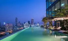 Luxurious rooftop infinity pool with stunning city skyline view at dusk.
