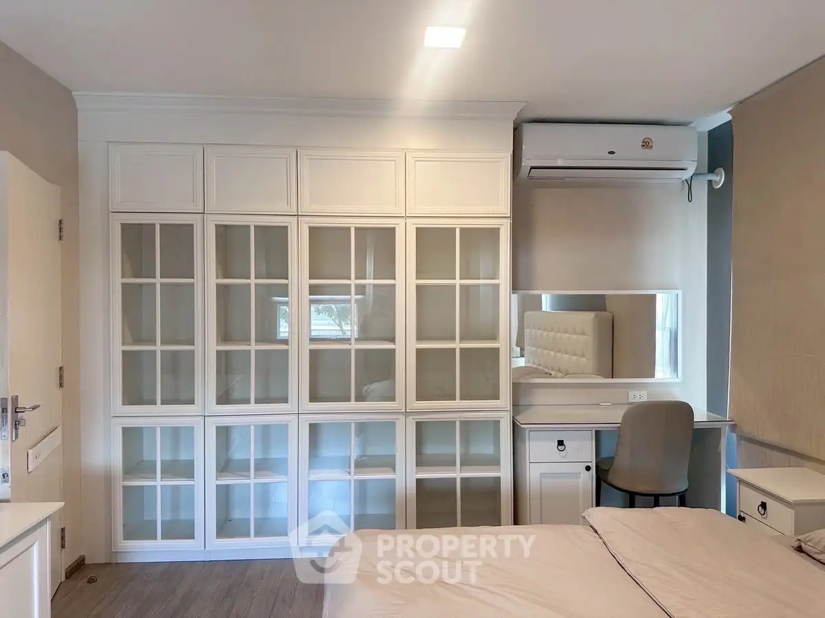 Elegant bedroom with built-in glass cabinets and cozy workspace