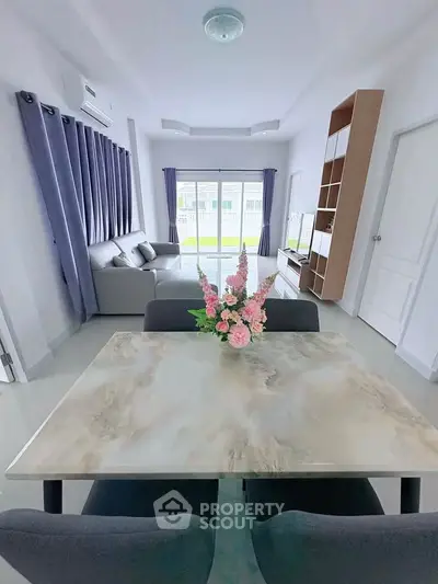 Modern living room with elegant dining area and large windows for natural light.
