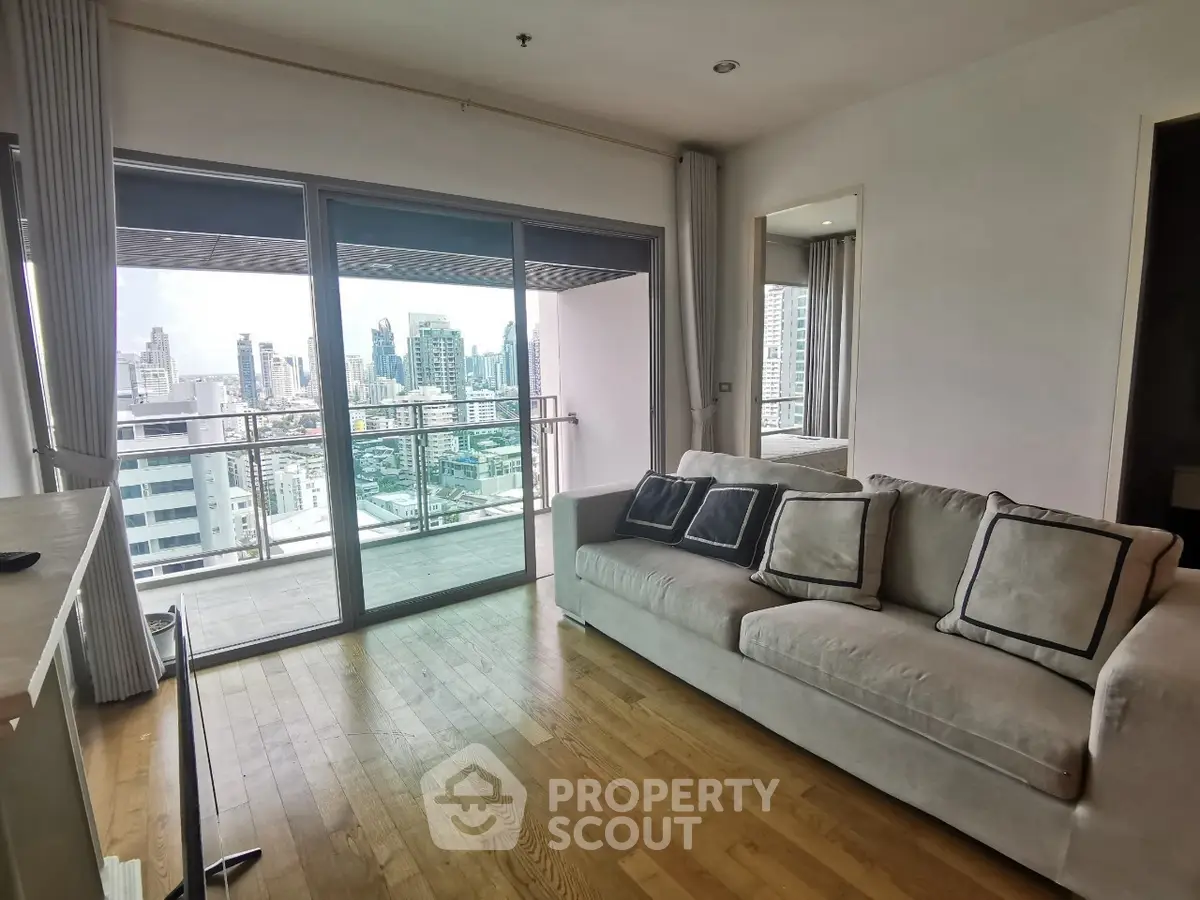 Modern living room with city view and spacious balcony in high-rise apartment.