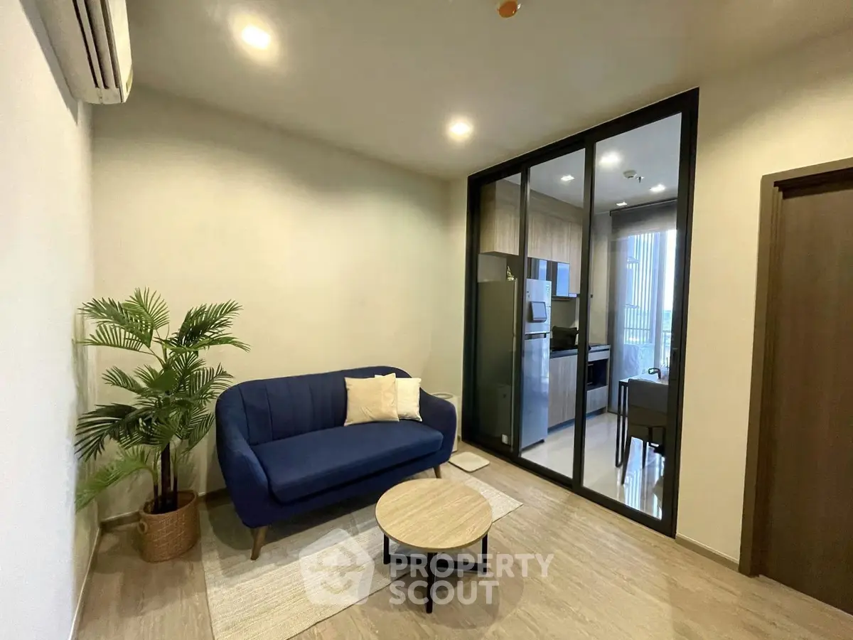 Modern living room with blue sofa and open kitchen layout in stylish apartment