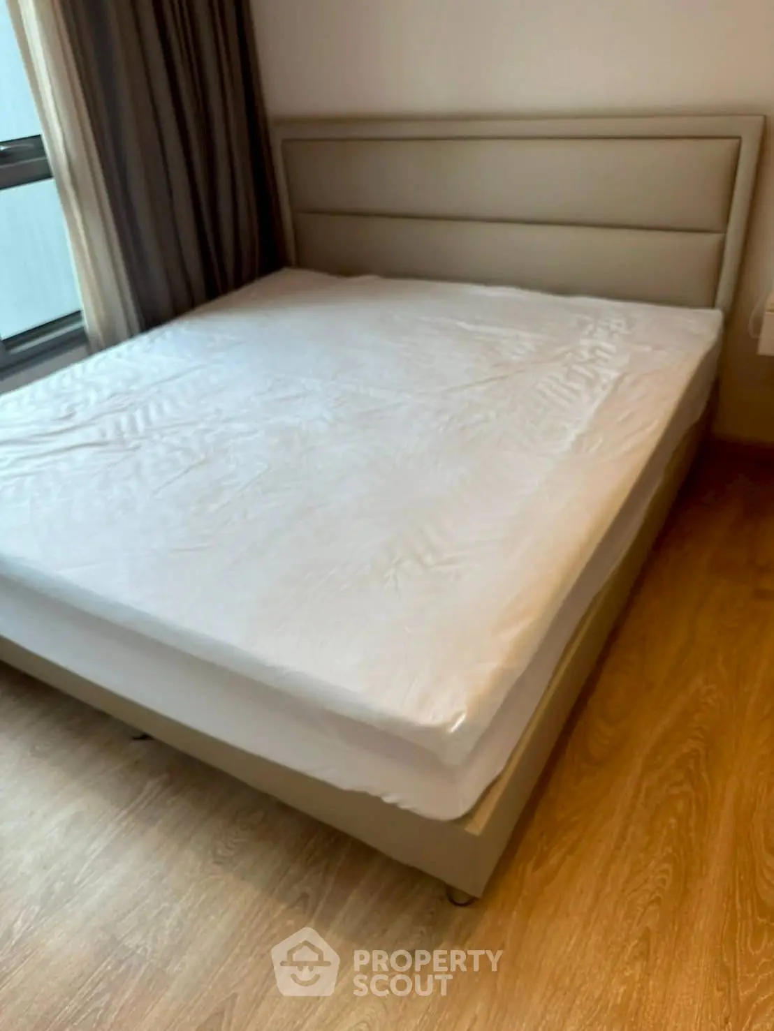 Spacious bedroom with modern bed and wooden flooring in a cozy apartment.