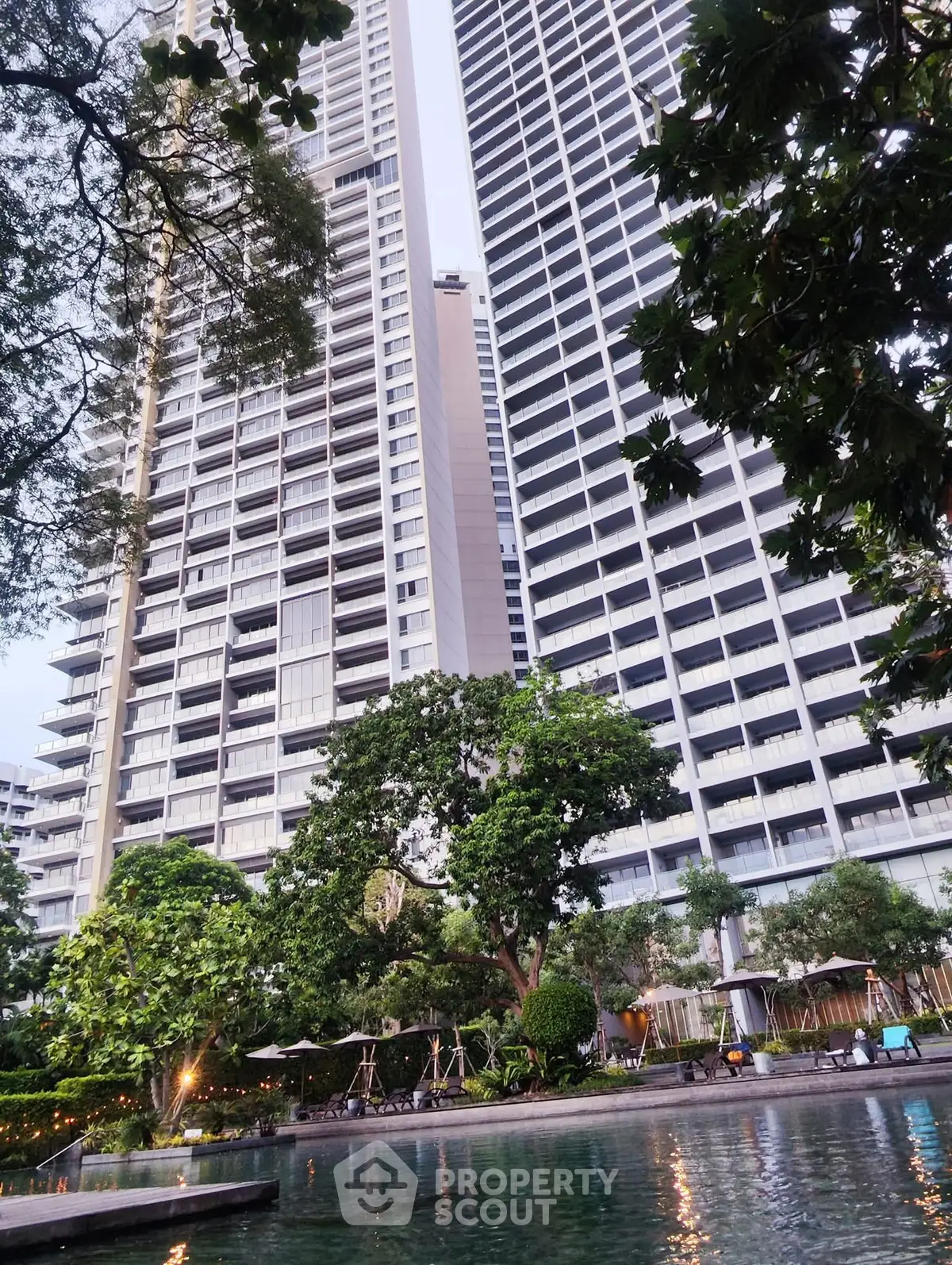 Luxurious high-rise building with lush garden and pool view, perfect for urban living.