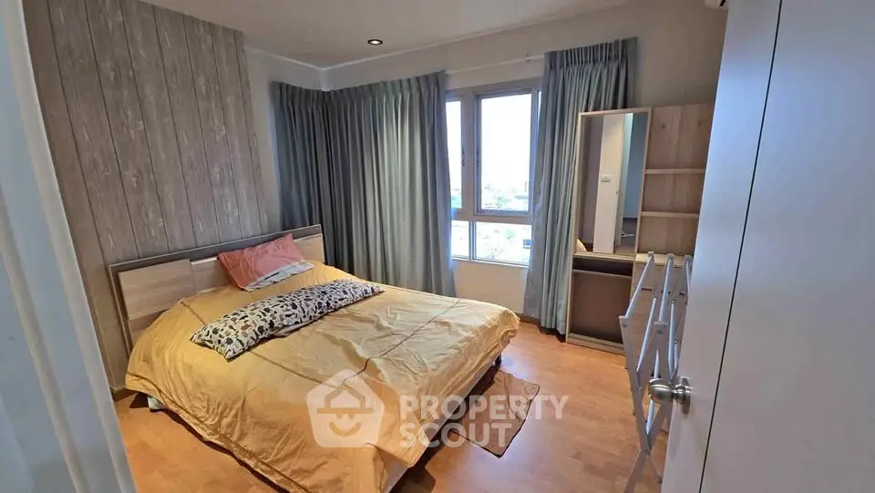 Cozy bedroom with wooden flooring and large window offering natural light