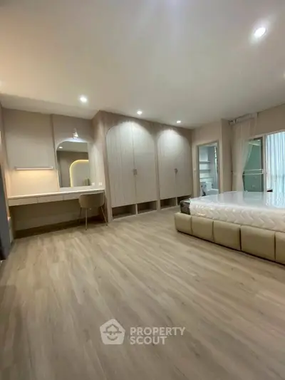 Spacious modern bedroom with elegant wood flooring and built-in wardrobe