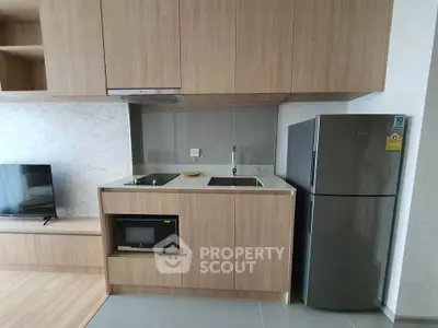 Modern kitchen with sleek wooden cabinetry and stainless steel appliances in a compact layout.