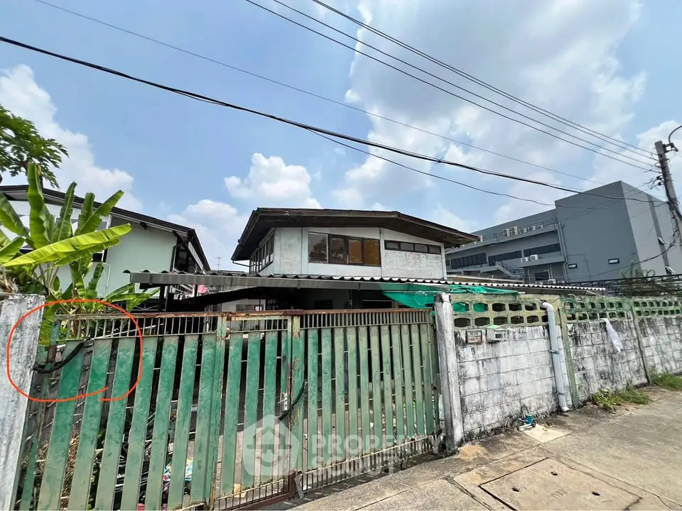 Charming two-story house with gated entrance and lush greenery, perfect for family living in a serene neighborhood.