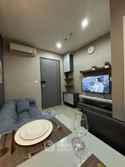 Modern living room with cozy sofa, dining setup, and wall-mounted TV in stylish apartment.