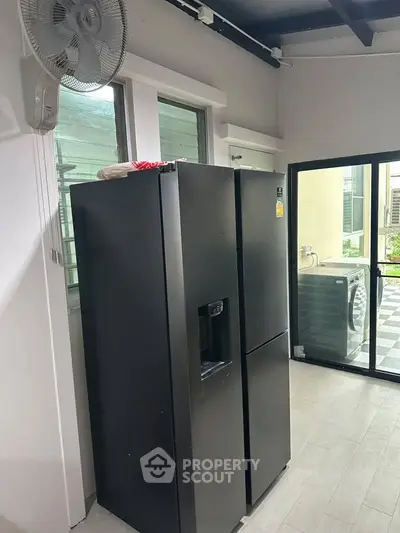 Modern kitchen with sleek black refrigerator and outdoor view