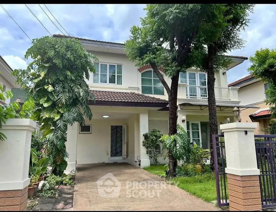 Charming two-story house with lush greenery and spacious driveway in a serene neighborhood.