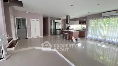 Spacious open-plan living area with modern kitchen and large windows in a stylish home.