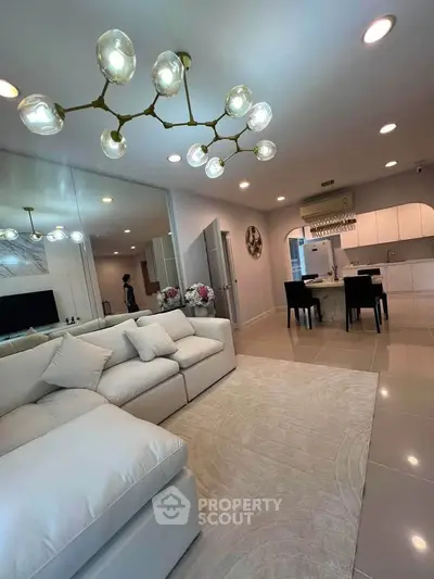Luxurious open-plan living room with elegant chandelier and modern kitchen
