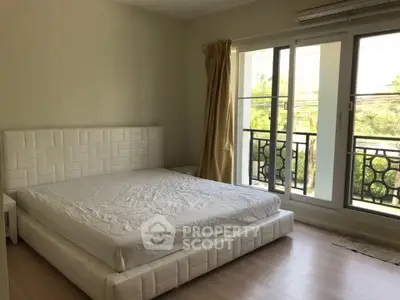 Spacious bedroom with large windows and balcony access in modern apartment.