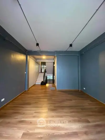 Spacious open-plan interior with modern wooden flooring and sleek lighting, perfect for versatile living or office space.