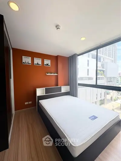 Modern bedroom with large window and city view, featuring sleek design and ample natural light.