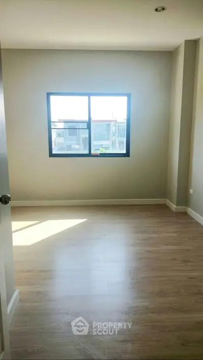 Bright empty room with wooden flooring and large window in modern apartment