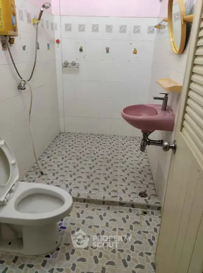 Compact bathroom with pink sink and tiled floor