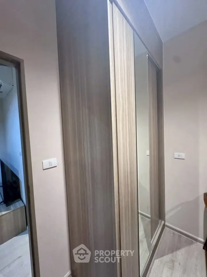 Modern interior with sleek wooden wardrobe and mirrored sliding doors in a stylish apartment.