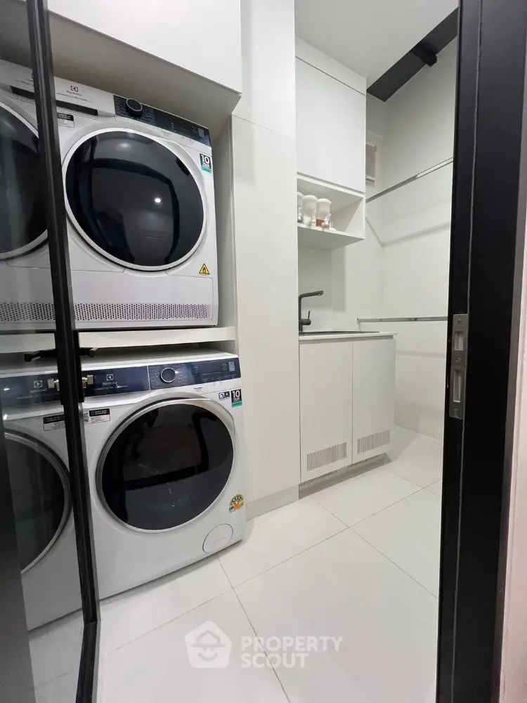 Modern laundry room with stacked washer and dryer in sleek white cabinetry