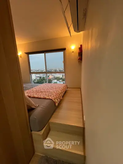 Cozy bedroom with elevated bed and panoramic city view from large window.