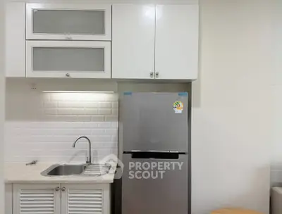 Modern kitchen with sleek cabinetry and stainless steel fridge in a compact layout.