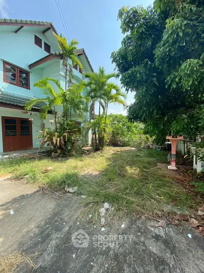 Charming two-story home nestled among lush greenery with a spacious front yard, offering a serene tropical living experience.