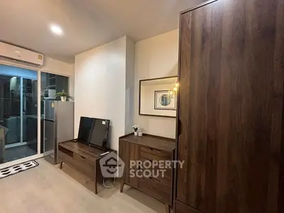 Modern living room with wooden furniture and sliding glass door to balcony.