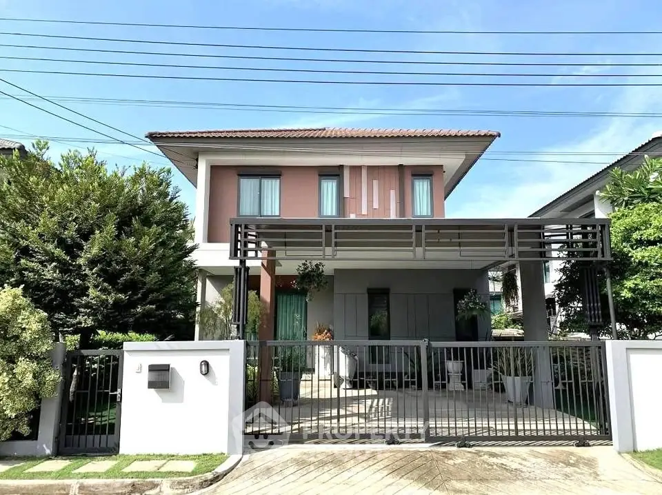 Modern two-story house with gated driveway and lush greenery