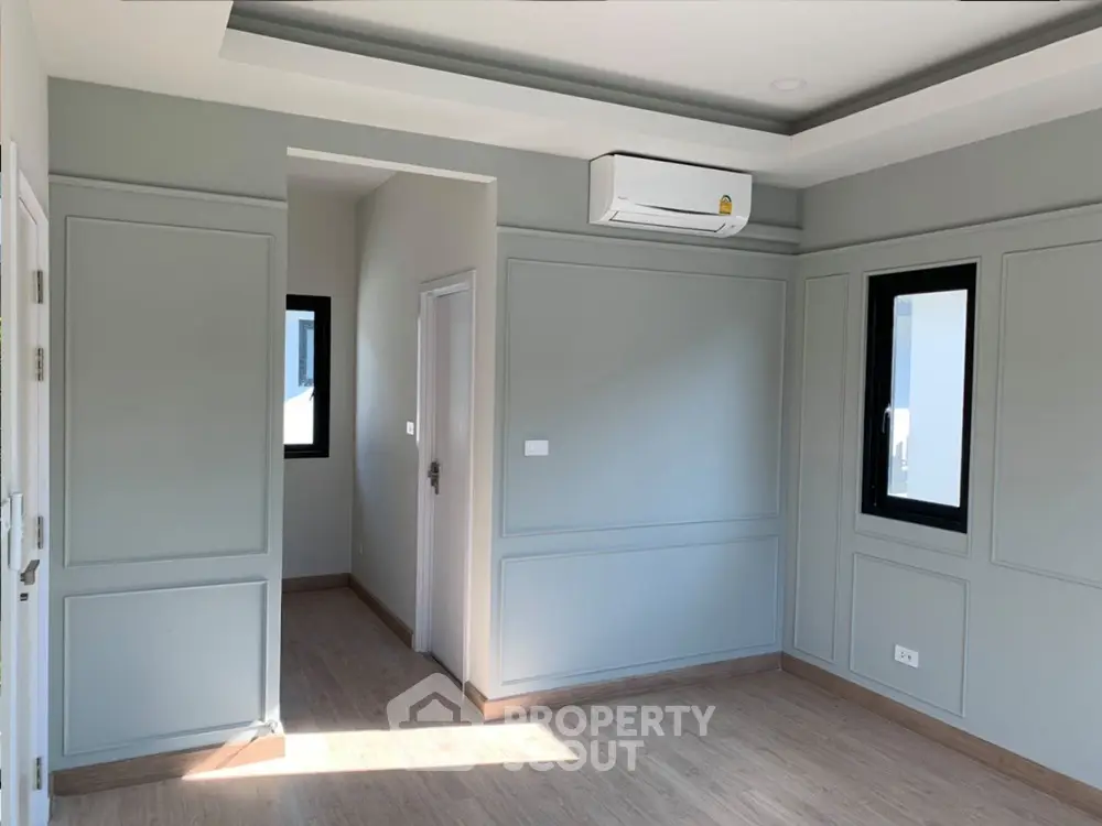 Spacious and well-lit corner unit with modern air conditioning, elegant wooden flooring, and multiple windows offering ample natural light, ideal for a comfortable living space.