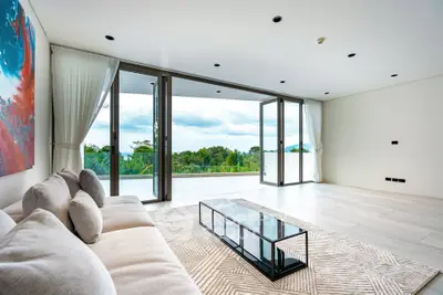 Luxurious living room with stunning view and modern decor, featuring large glass doors opening to a spacious balcony.