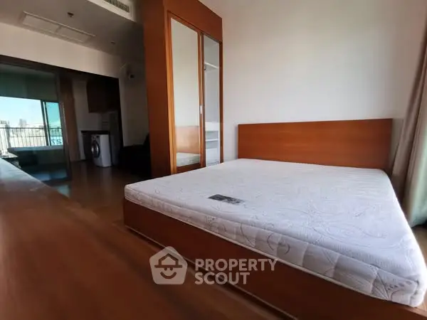 Spacious bedroom with wooden furniture and balcony view in modern apartment.