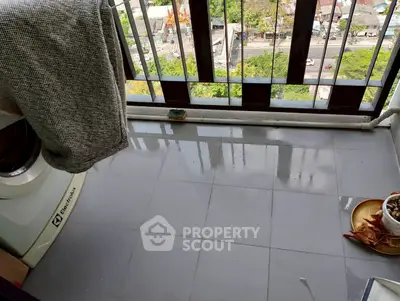 Spacious balcony with city view and modern washing machine, perfect for urban living.