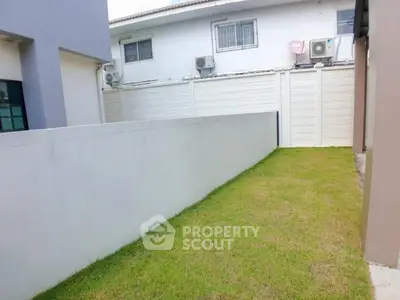 Spacious backyard with lush green lawn and privacy fence in modern residential area.