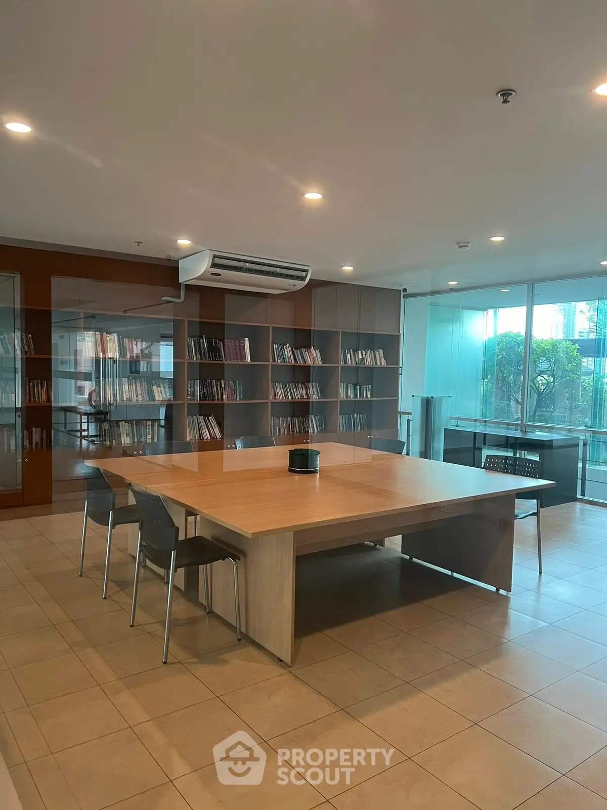 Modern library with sleek wooden table and bookshelves in a bright, airy space.